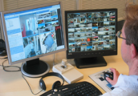 Una persona mira dos monitores. Los monitores muestran vistas XProtect Smart Client.